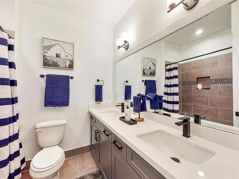 A modern bathroom with a white bathtub, a walk-in shower, and a vanity. The bathroom has white subway tiles with gray veining throughout. The walls are a light cream color, and the lighting is bright. There is a window above the bathtub, letting in natural light.