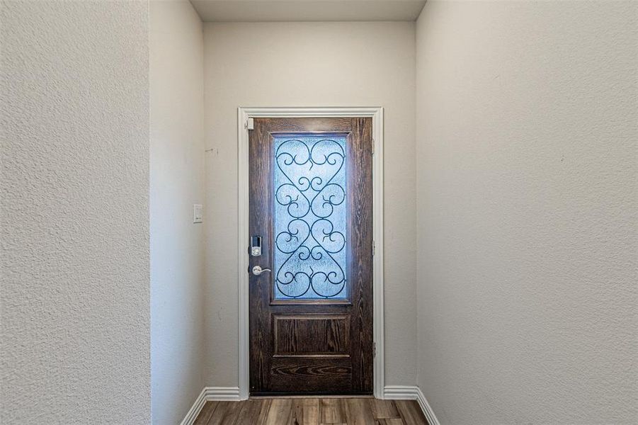 Doorway to outside featuring dark wood finished floors, a textured wall, and baseboards