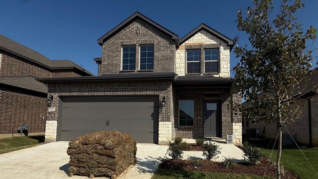 Traditional-style home featuring brick siding, driveway, a garage, stone siding, and covered porch Traditional-style home featuring brick siding, driveway, a garage, stone siding, and covered porch
