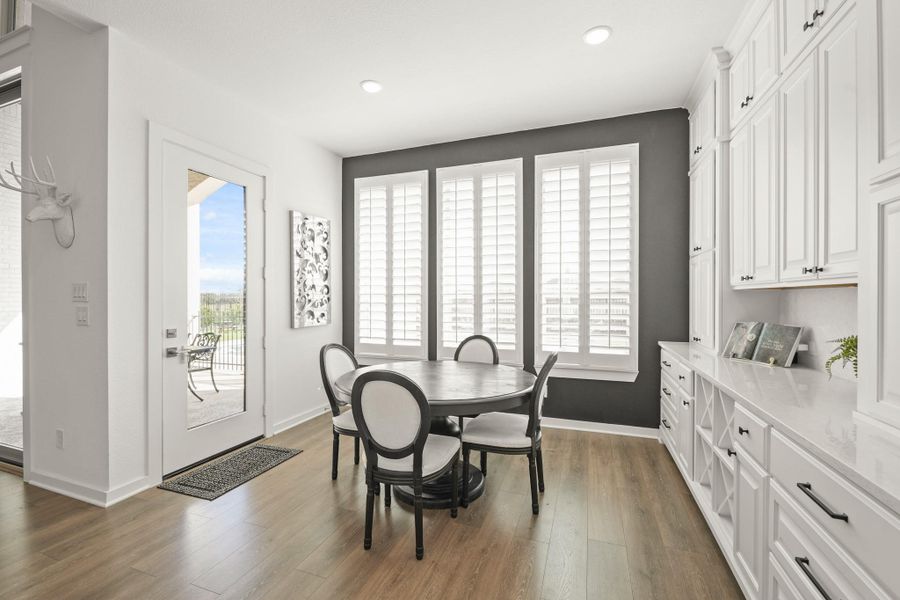 The breakfast room features Revwood floors and three windows with plantation shutters that overlook the backyard, lake, pool and spa. An 8-foot glass door leads to the covered patio, adding light and easy access to the outdoors. To the right are built-in wine racks along with addition counterspace and storage.