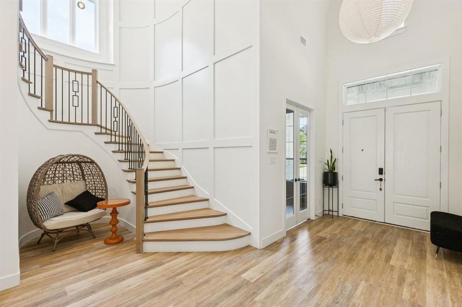 Foyer featuring light wood finished floors, stairs, and a towering ceiling