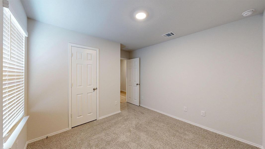 A well-lit bedroom features plush carpeting and classic white doors, creating a serene and inviting atmosphere.