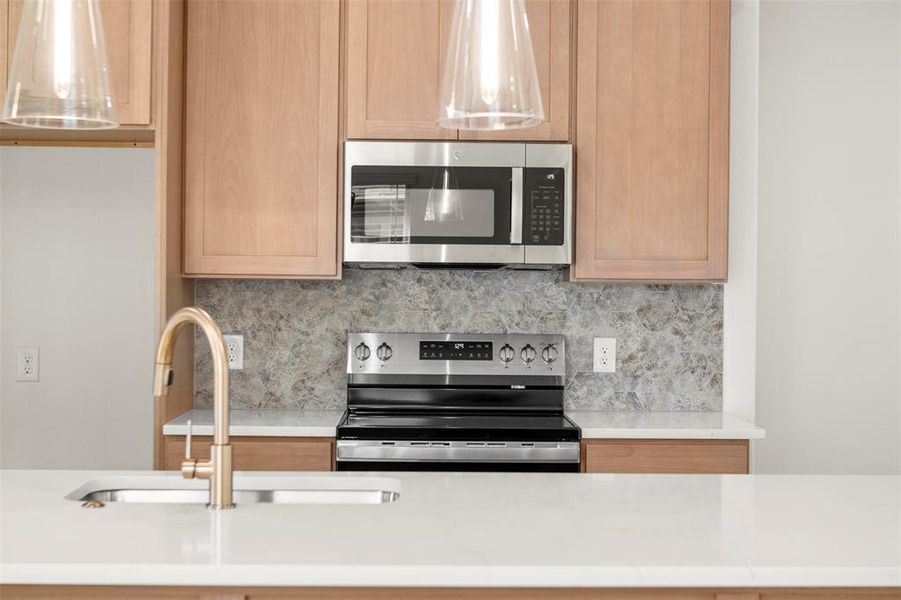 Kitchen with tasteful backsplash, appliances with stainless steel finishes, and light stone countertops