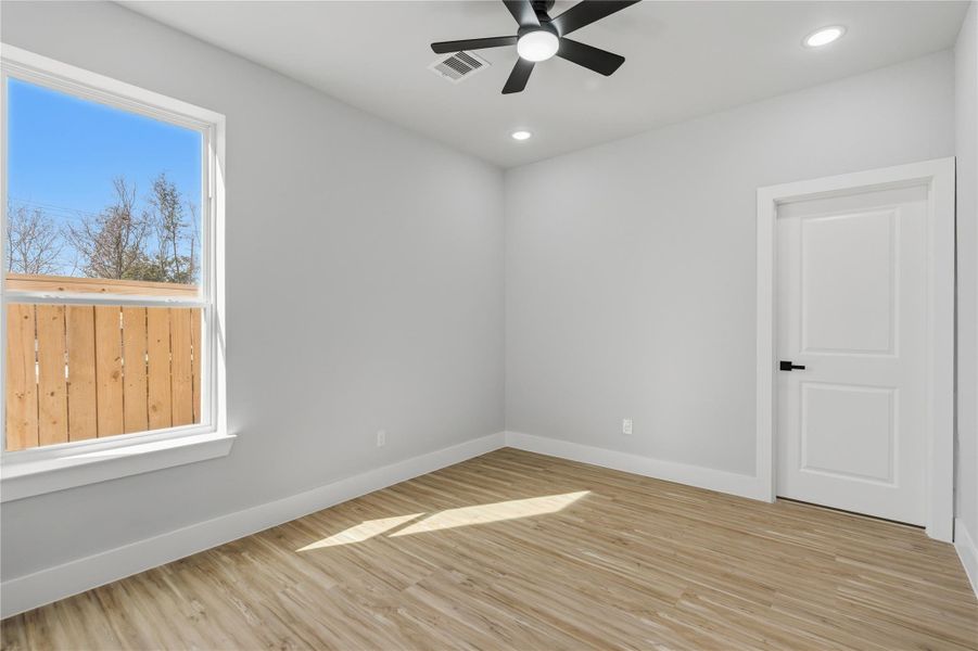 Light-filled bedroom with modern ceiling fan, fresh finishes, and warm wood flooring.
