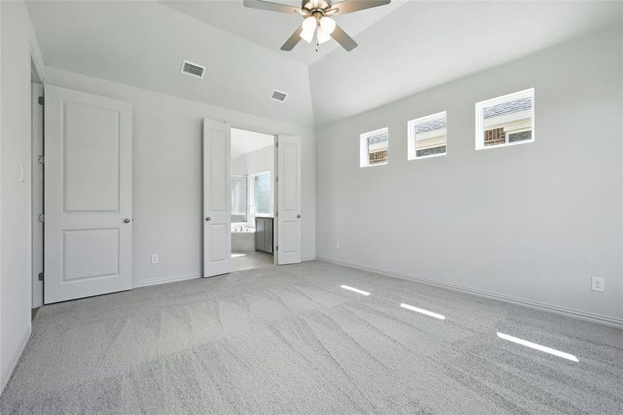 Unfurnished bedroom with carpet, high vaulted ceiling, ensuite bath, and ceiling fan Unfurnished bedroom with carpet, high vaulted ceiling, ensuite bath, and ceiling fan