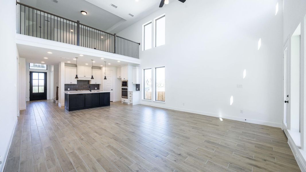 Unfurnished living room featuring light wood-style flooring, a high ceiling, a ceiling fan, and recessed lighting