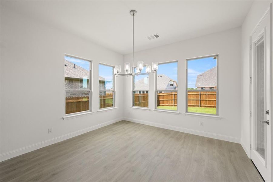 Unfurnished dining area featuring a chandelier and light wood finished floors Unfurnished dining area featuring a chandelier and light wood finished floors