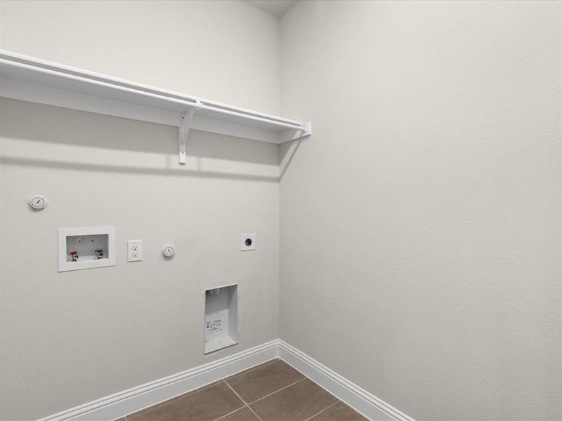 Laundry room with hookup for a gas dryer, dark tile patterned flooring, electric dryer hookup, and washer hookup