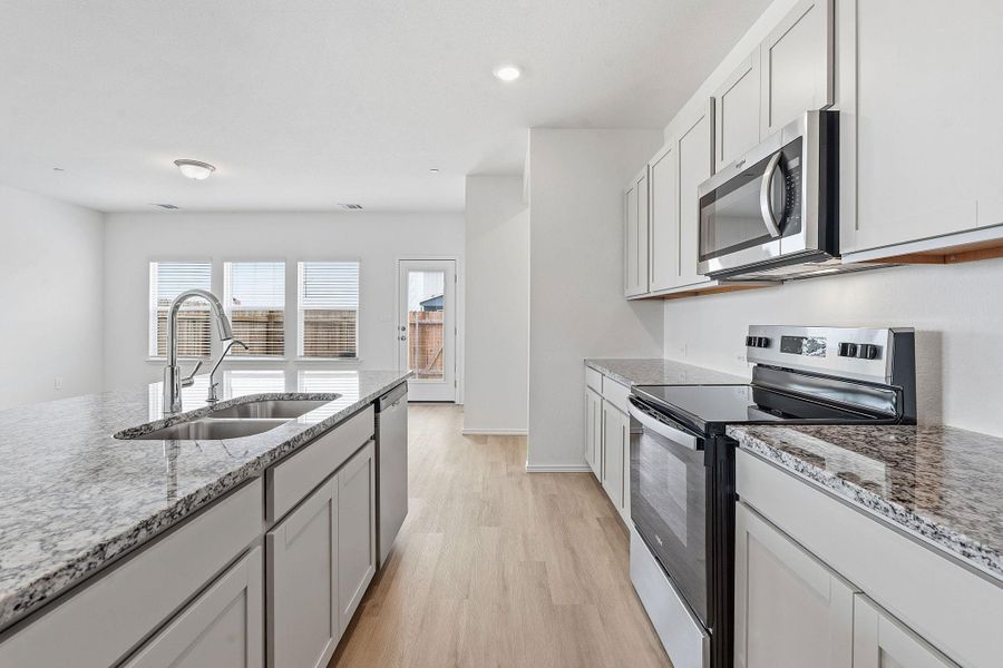 Modern kitchen featuring light wood-finish flooring, white cabinetry, and light-toned stone countertops Modern kitchen featuring light wood-finish flooring, white cabinetry, and light-toned stone countertops