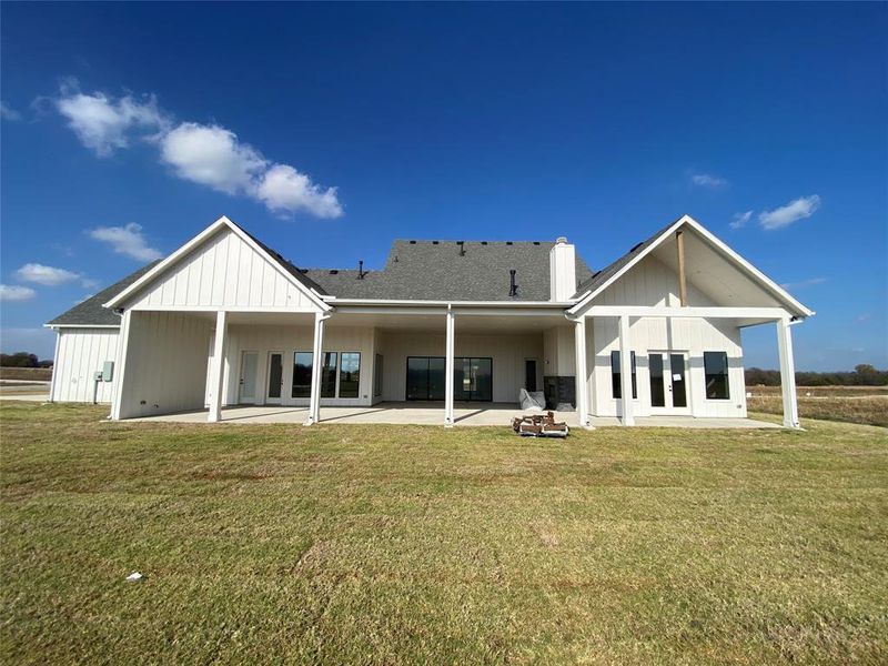 Back of house with a patio, a yard, a chimney, board and batten siding, and french doors