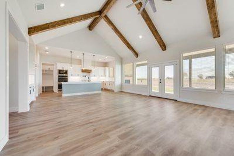 Unfurnished living room featuring light hardwood / wood-style floors, high vaulted ceiling, and beamed ceiling