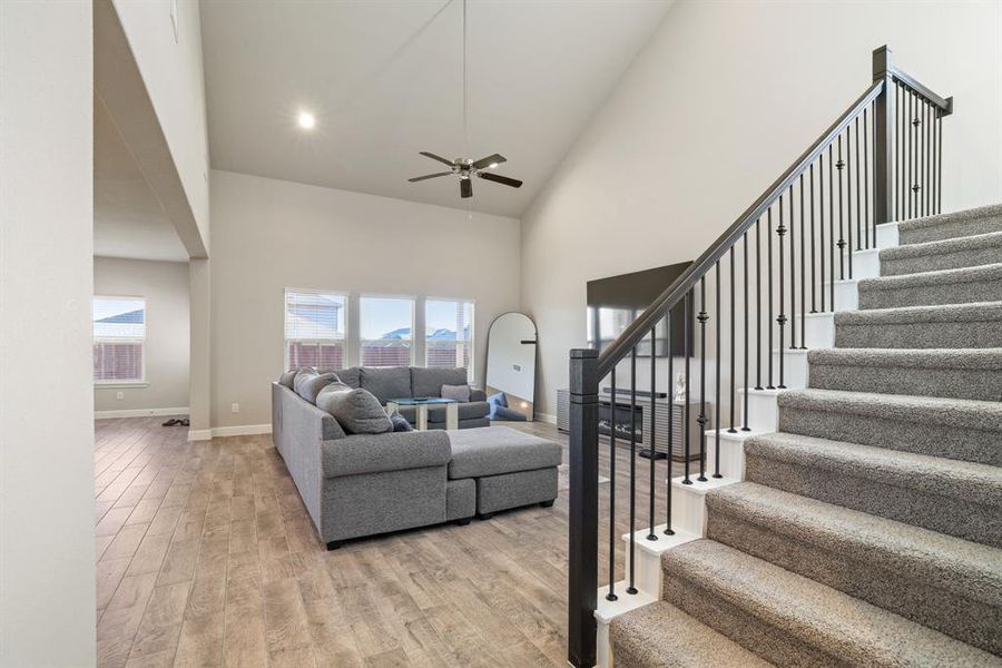 Living area featuring light wood-style floors, lofted ceiling, a ceiling fan, and recessed lighting Living area featuring light wood-style floors, lofted ceiling, a ceiling fan, and recessed lighting