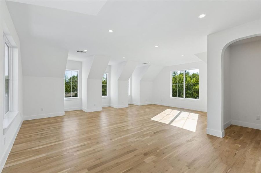Unfurnished living room featuring recessed lighting, arched walkways, vaulted ceiling, and light wood finished floors