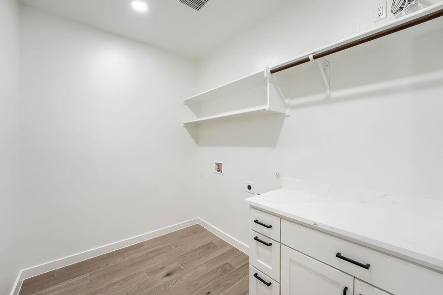 A dedicated laundry room with ample counter space and storage shelving.