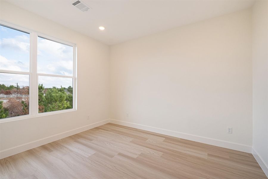 Empty room with light wood finished floors and recessed lighting