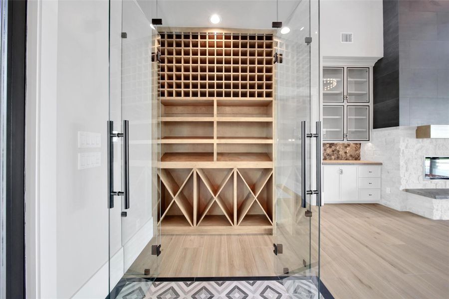 A wine and spirits open-concept display is just off the entryway and is made from solid maple wood and enclosed in a frameless case with modern decorative tile flooring.