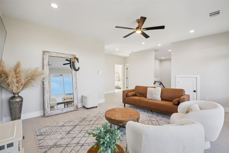 Living room with a ceiling fan, light wood-style floors, and recessed lighting