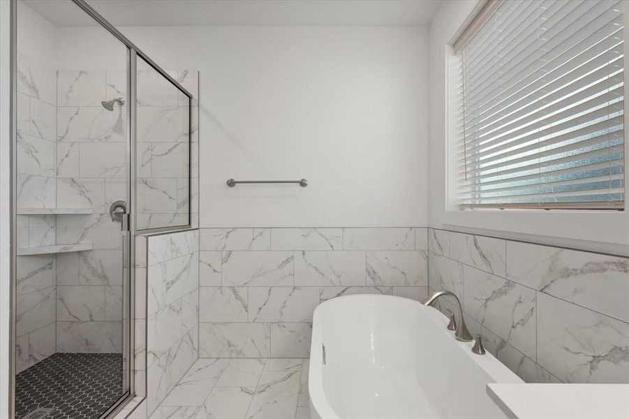 Luxurious Primary Bath featuring a beautiful designer ceramic tile shower, a 42" oval freestanding bath, designer ceramic tile walls & double granite vanity cabinets .