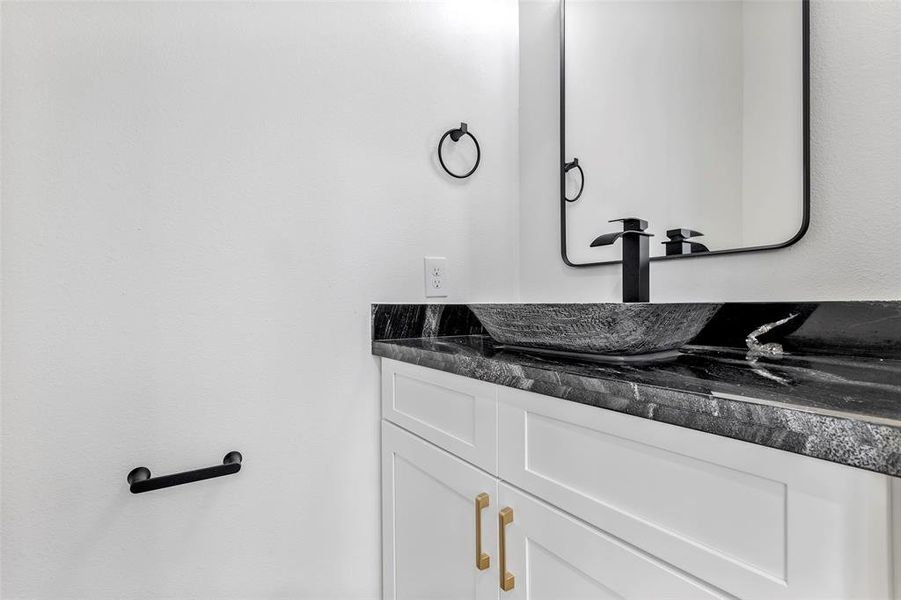 The half bathroom with quartz countertops and cabinets for storage.