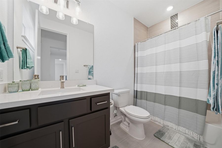 Bathroom featuring a dark wood vanity with a white countertop, a mirror, and a shower with a tiled surround