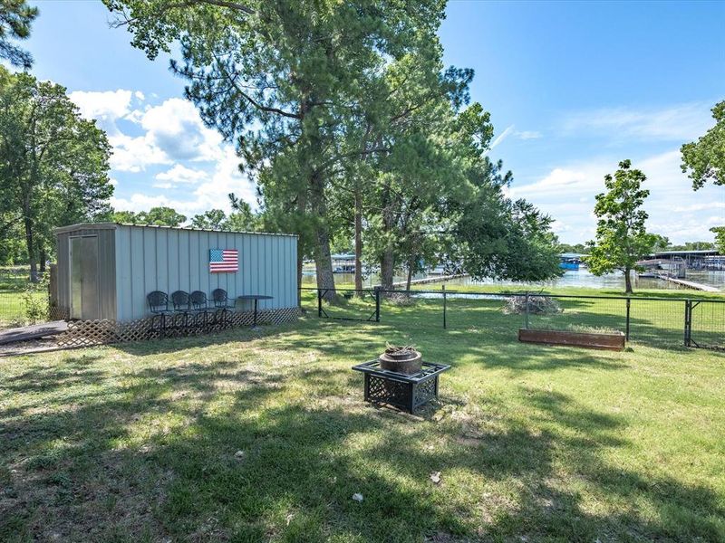 View of yard with a water view, a fire pit, and an outbuilding View of yard with a water view, a fire pit, and an outbuilding