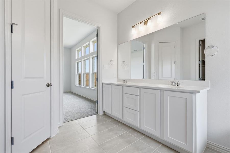 Bathroom featuring double vanity, light tile patterned floors, and light carpet