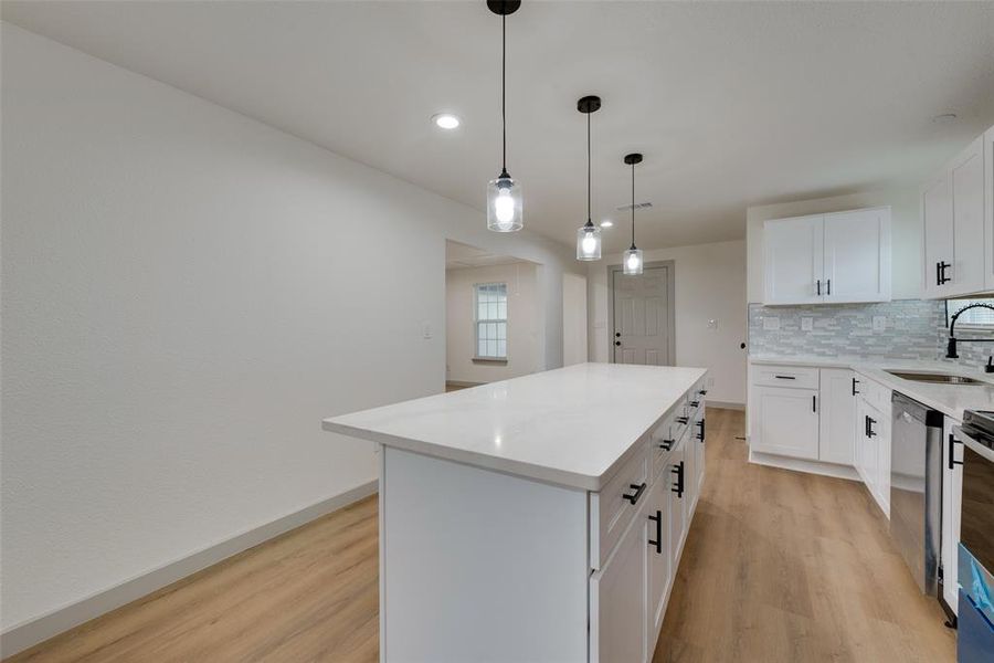 Kitchen featuring white cabinets, a center island, and light hardwood / wood-style flooring