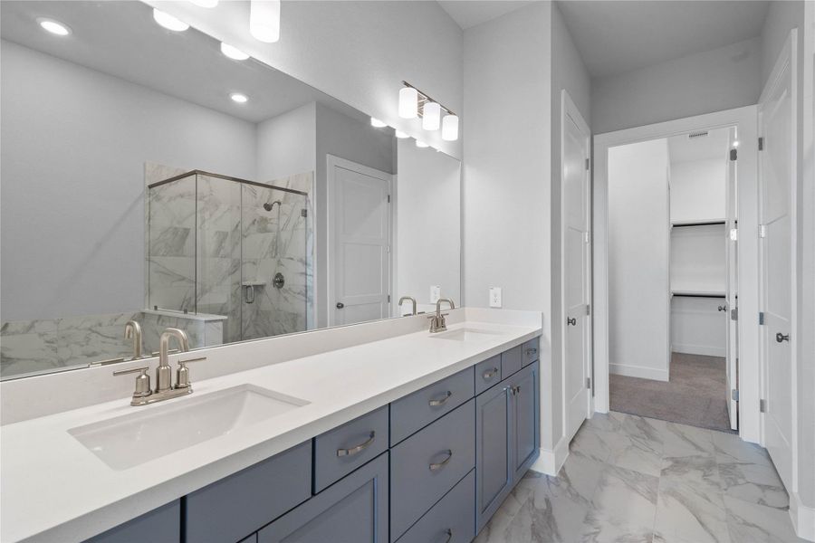 Retreat to a private, spa-like primary bathroom designed for relaxation and convenience. A generous double vanity with modern cabinetry offers ample space for two people. The connecting walk-in closet makes getting ready convenient.