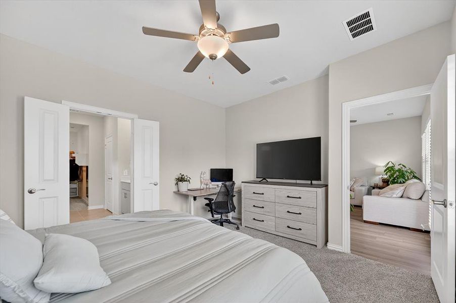 Bedroom featuring a ceiling fan, light carpet, and an office area