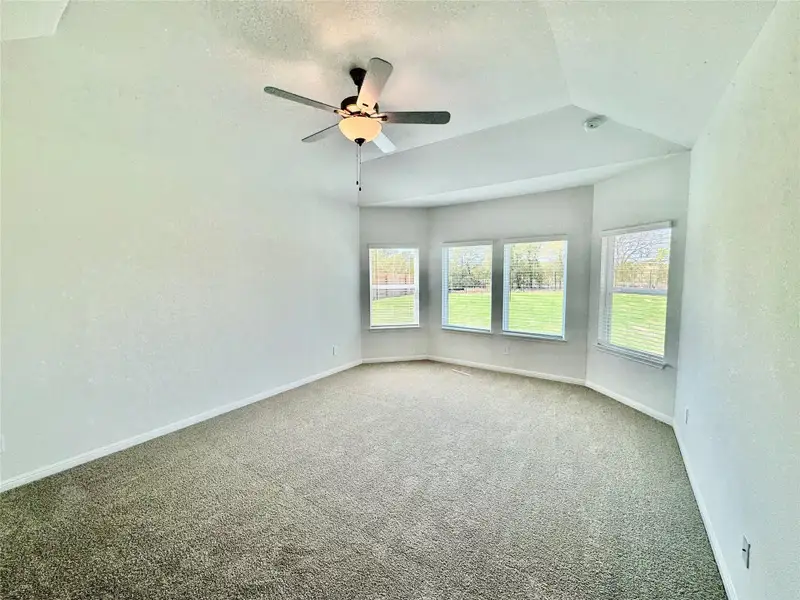 Unfurnished room with a textured ceiling, carpet, lofted ceiling, and a ceiling fan