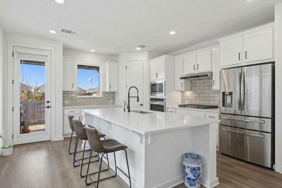 A pristine culinary space awaits, boasting an inviting central island and sleek, contemporary finishes.