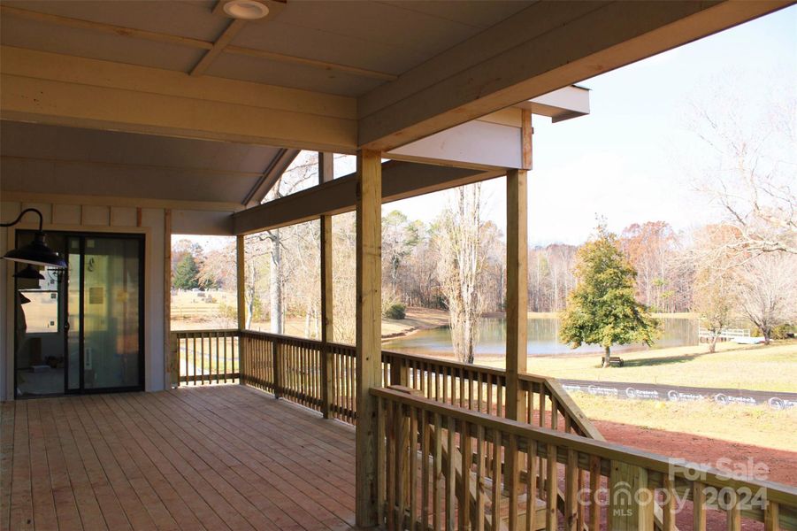 Covered back porch with serene pond views and outdoor living potential.