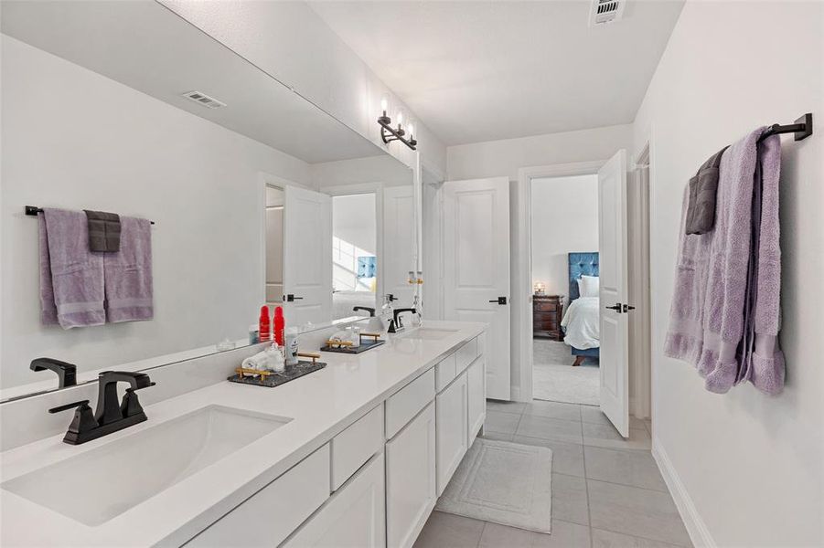 Ensuite bathroom featuring double vanity and light tile patterned floors