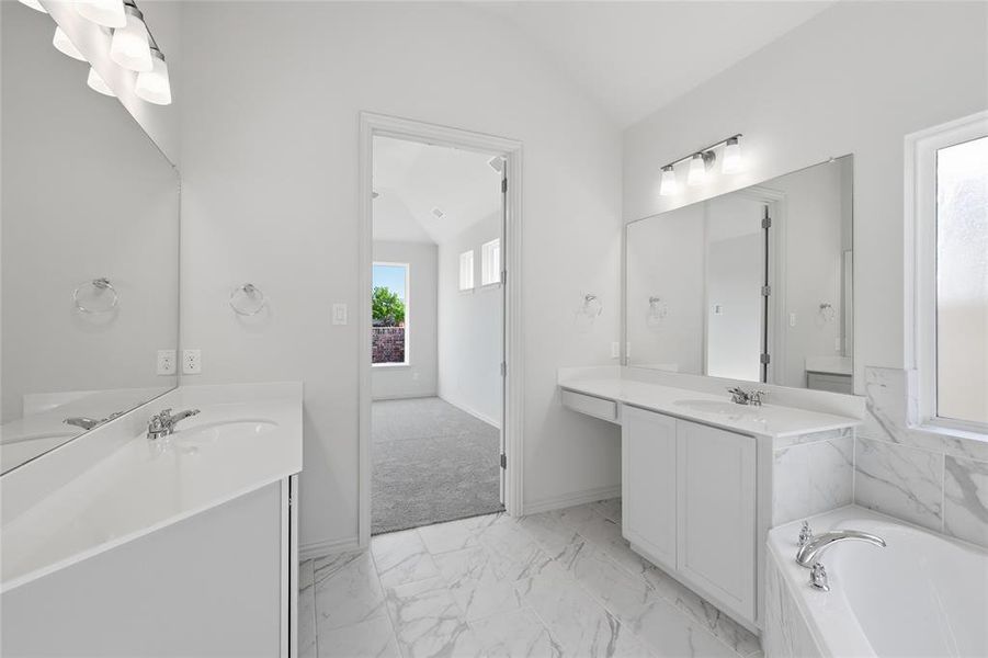 Full bathroom with light marble finish floors, two vanities, a garden tub, and lofted ceiling Full bathroom with light marble finish floors, two vanities, a garden tub, and lofted ceiling