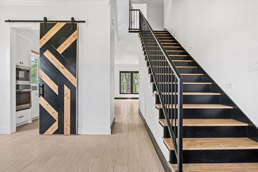 Stairs with a barn door and wood finished floors