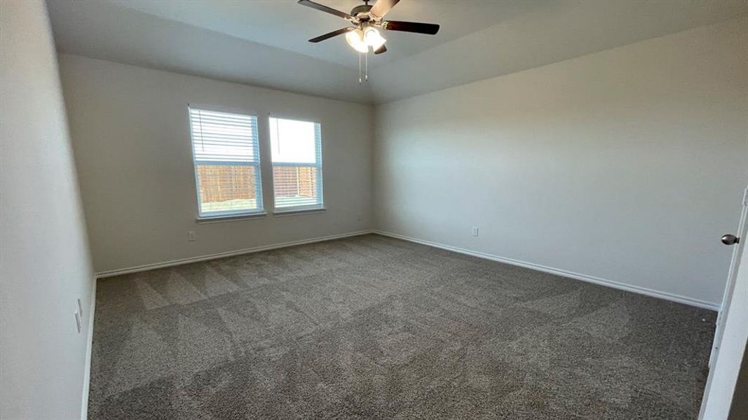 Spacious room featuring neutral carpeting, light-toned walls, and a ceiling fan with integrated lighting