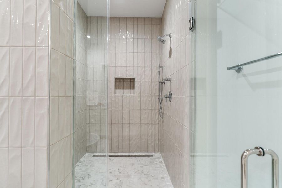 Seamless glass shower door leads to a walk-in shower accented with gorgeous porcelain tile and built-in shower seat Seamless glass shower door leads to a walk-in shower accented with gorgeous porcelain tile and built-in shower seat