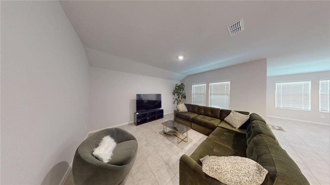 Spacious living area featuring neutral wall tones, recessed lighting, and large windows with blinds