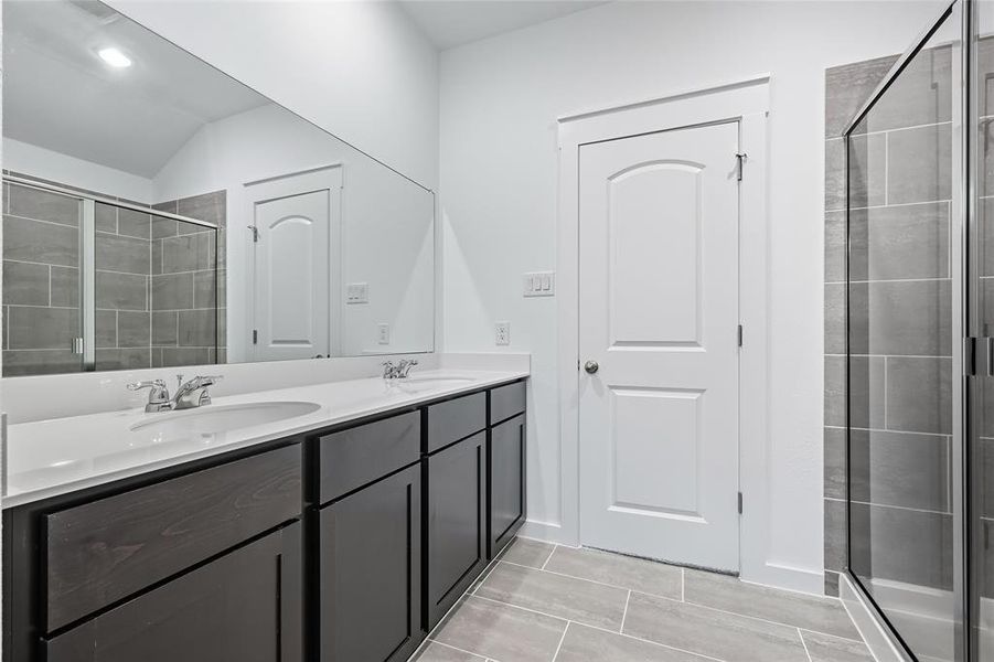 Bathroom featuring a stall shower and double vanity Bathroom featuring a stall shower and double vanity