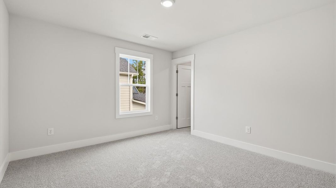 Elegant bedroom retreat featuring soft carpet and oversized windows that create a bright, welcoming space