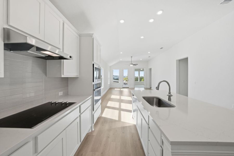 Kitchen featuring white cabinetry, recessed lighting, a center island with sink, light wood-style flooring, and light stone countertops Kitchen featuring white cabinetry, recessed lighting, a center island with sink, light wood-style flooring, and light stone countertops