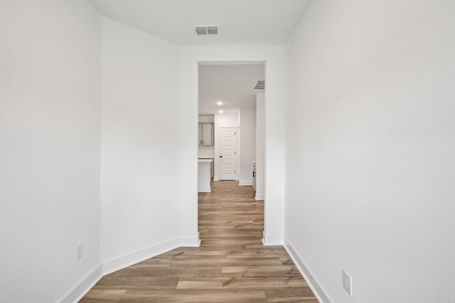 Elegant hallway features pristine white walls and exquisite light wood flooring at Spring Hill's Deering II residence.