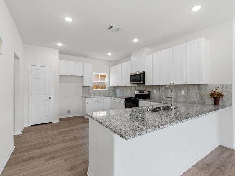 At the center of the home, the kitchen blends style and practicality with granite surfaces, stainless appliances, soft-close cabinetry, and abundant storage.