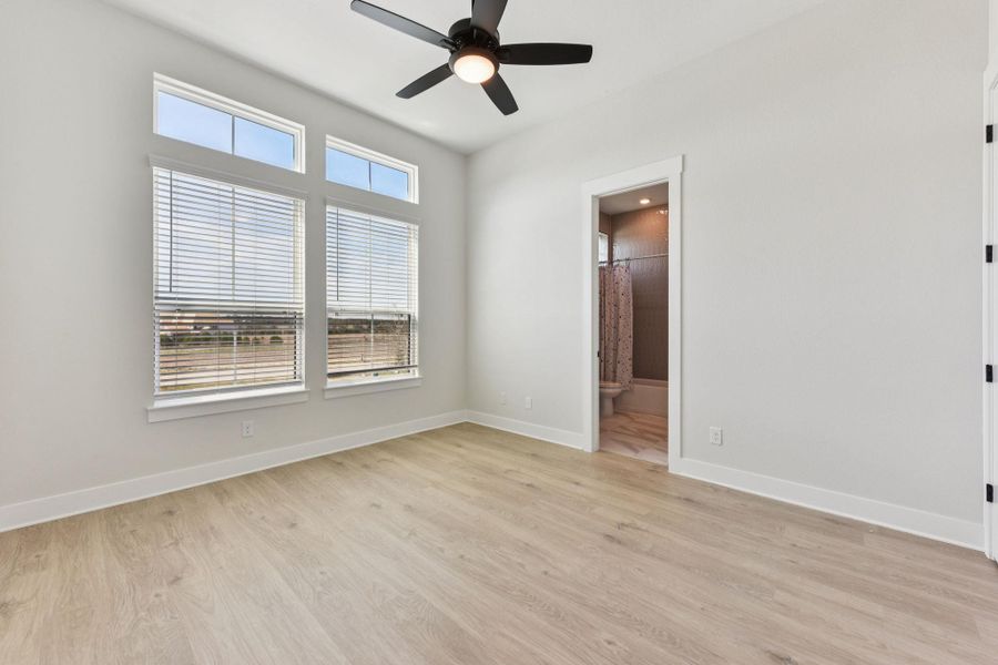 Unfurnished bedroom featuring light wood-style floors, a ceiling fan, and ensuite bathroom