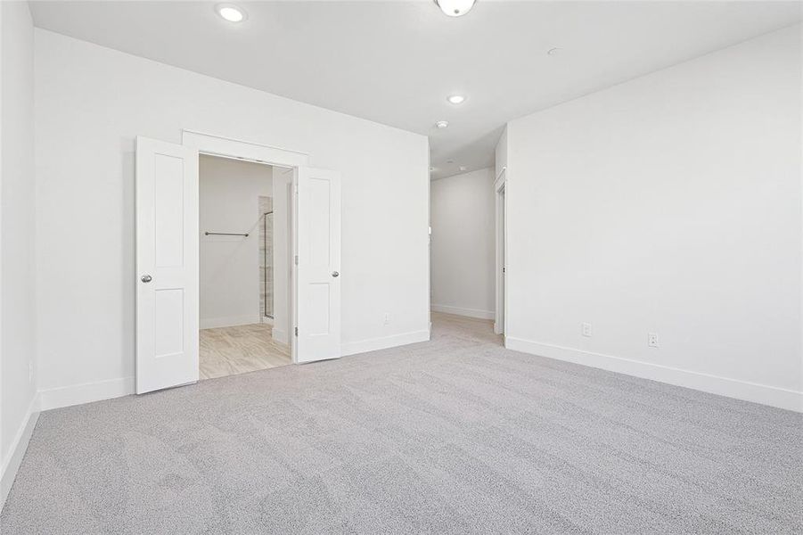 Spacious room featuring light gray carpet flooring, white walls, recessed lighting, and white baseboards