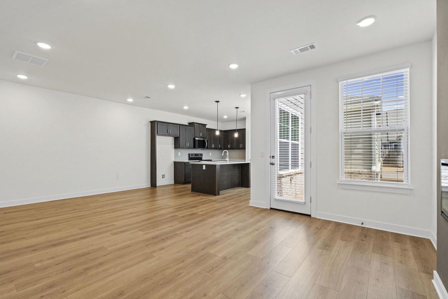 Open-concept living space featuring wood-finish flooring, recessed lighting, and a kitchen with dark cabinetry