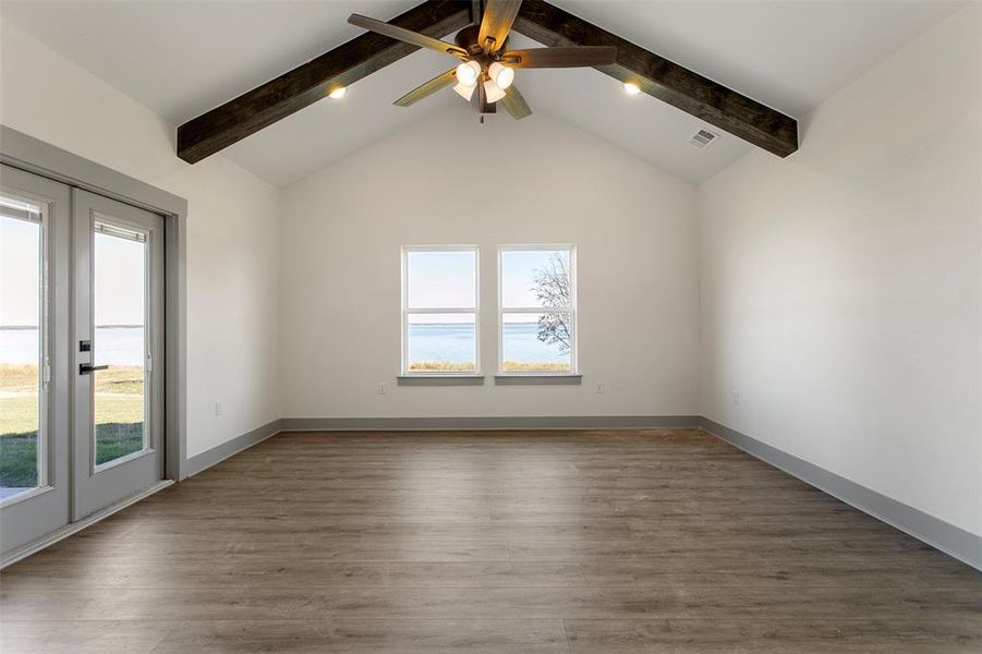 Unfurnished room with beam ceiling, dark hardwood / wood-style floors, plenty of natural light, and ceiling fan