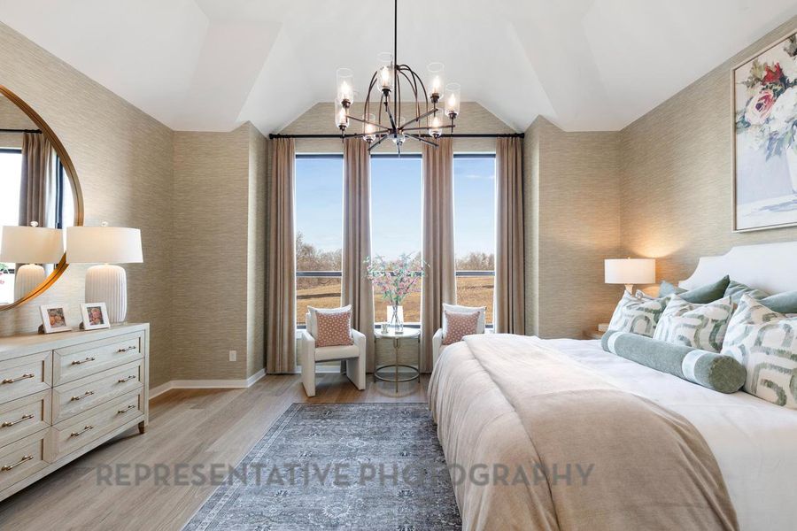 Bedroom with vaulted ceiling, wallpapered walls, an inviting chandelier, and light wood-type flooring