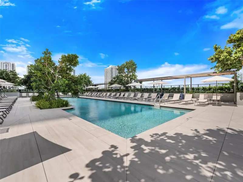 Swimming pool featuring a tiled deck, integrated landscape planters, and a covered pergola area Swimming pool featuring a tiled deck, integrated landscape planters, and a covered pergola area