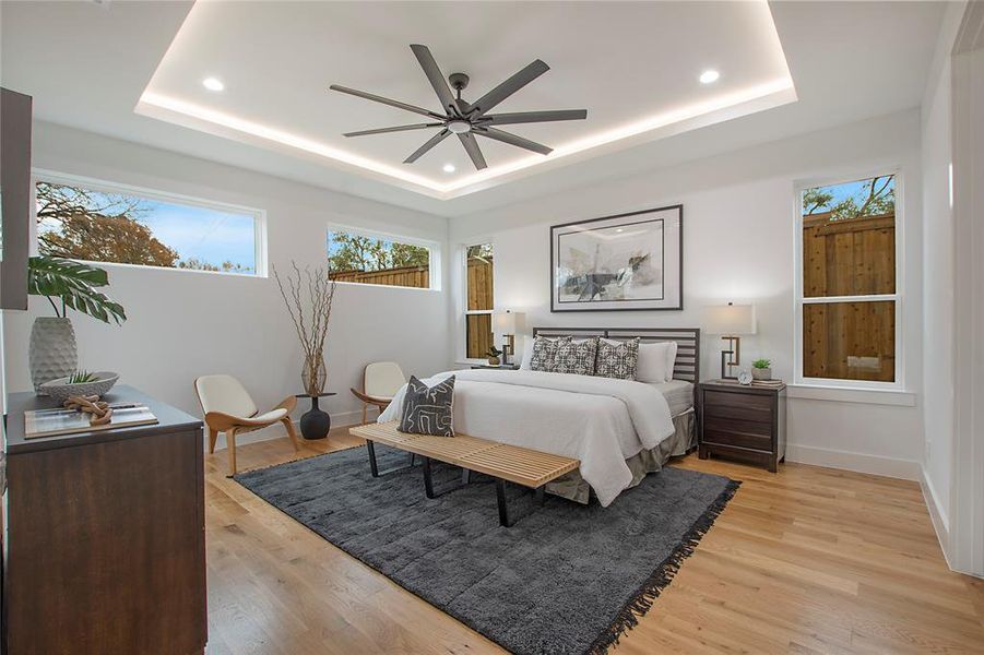 Bedroom featuring a tray ceiling, ceiling fan, and light wood-type flooring